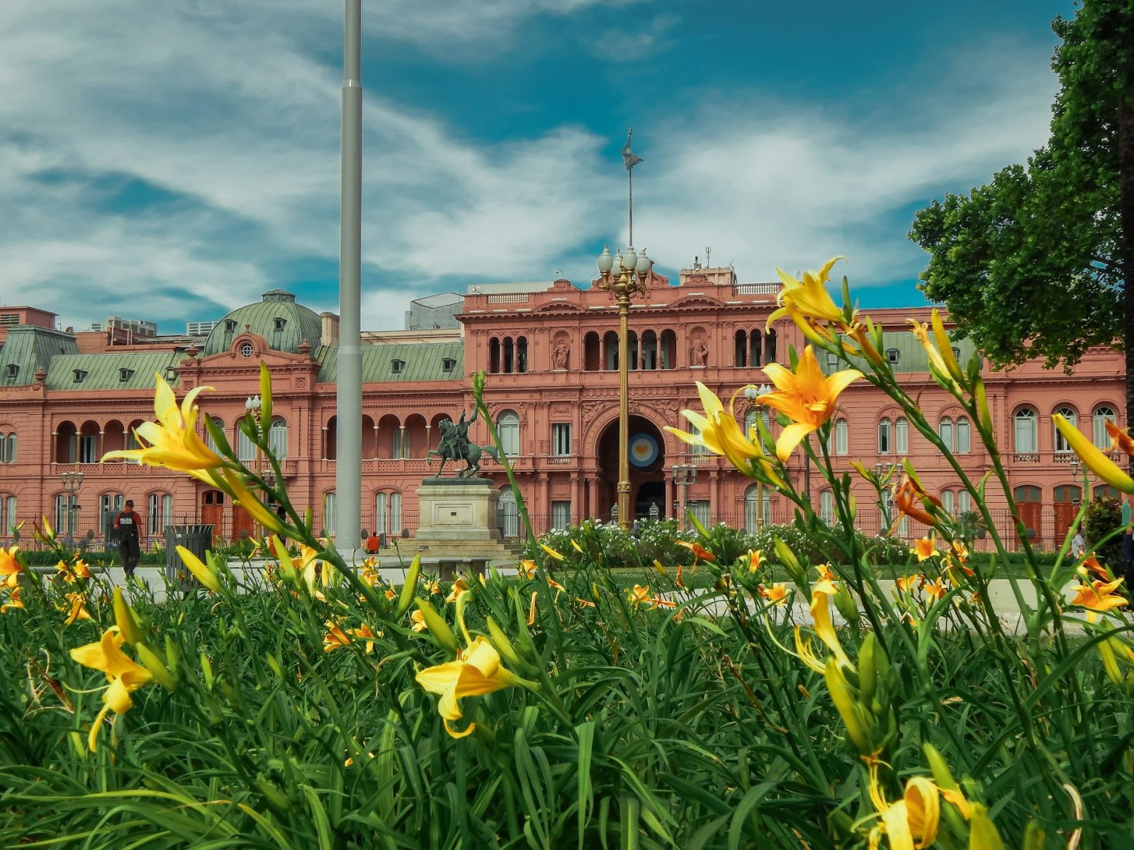 Foto da casa rosada em Buenos Aires. Flores amarelas na frente do edifício rosa.