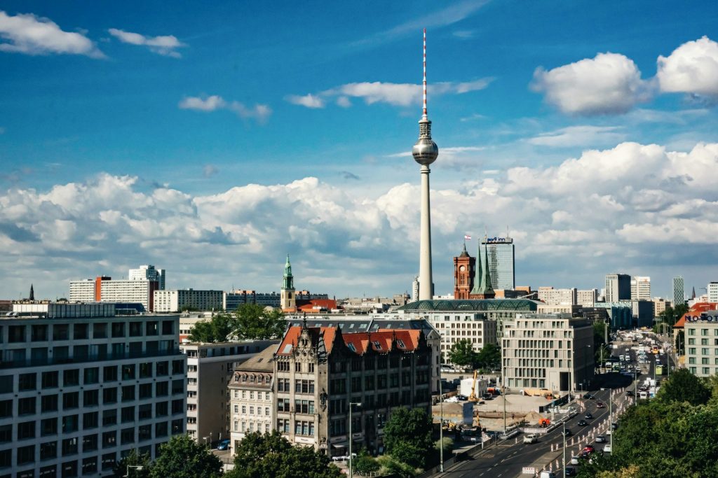 Alexanderplatz. Foto paisagem urbana com edificios, carros e uma construção alta com base de concreto e estrutura redonda no topo