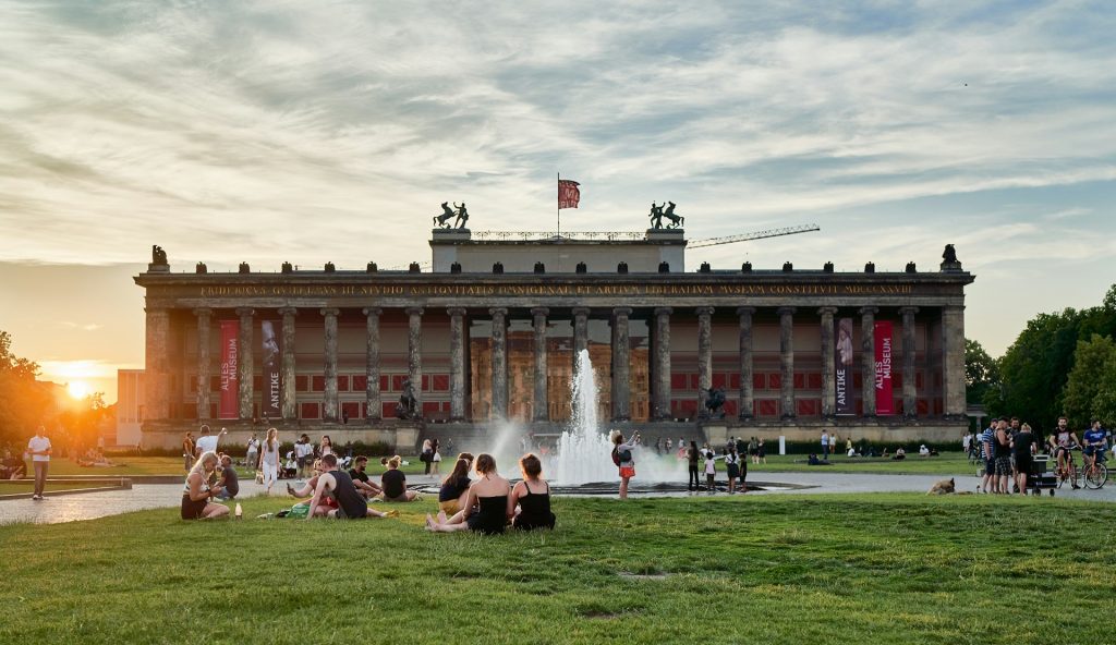 Altes Museum. Edificio grande com colunas na frente e um gramado com algumas pessoas passeando. 