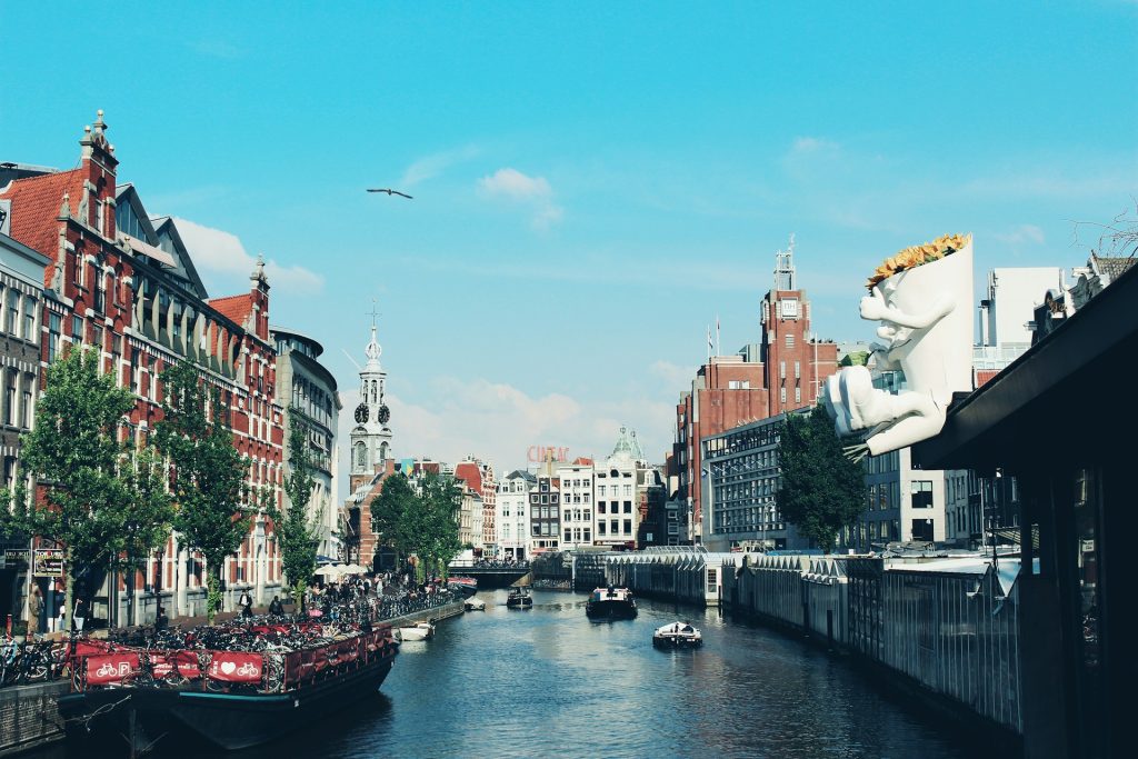 Amsterdam. Corpo de agua com barco e edifícios nas margens. 