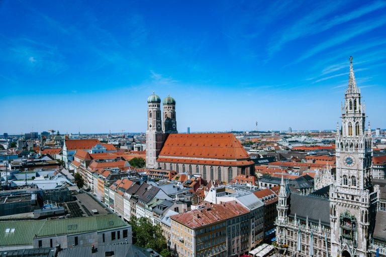 Frauenkirche Munique. Vista de uma cidade com uma grande construção no centro com duas torres bem altas.