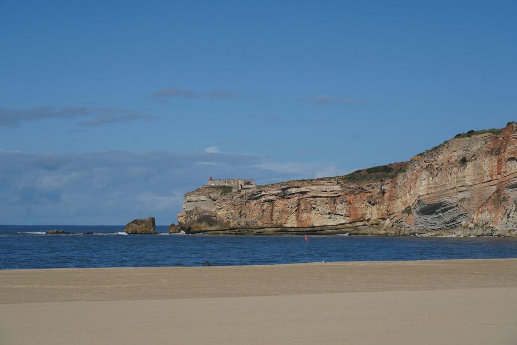 Nazaré. Praia perto de uma formação rochosa muito grande.