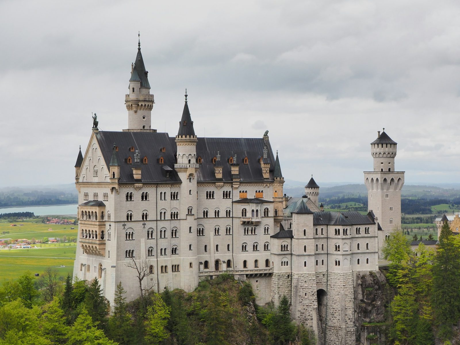 Neuschwanstein. Castelo bege perto de varias arvores.