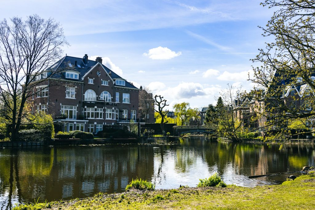 Vondelpark. corpo de agua com casa marrom ao fundo