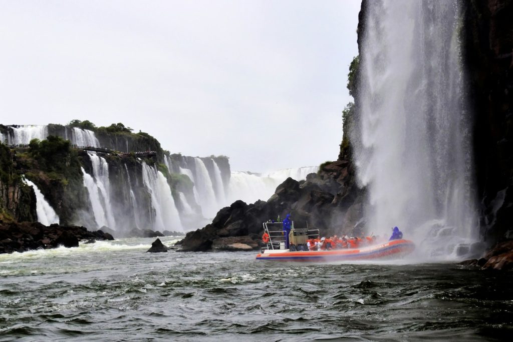 Foz do Iguaçu. Barco em corpo de agua perto de uma cachoeira.