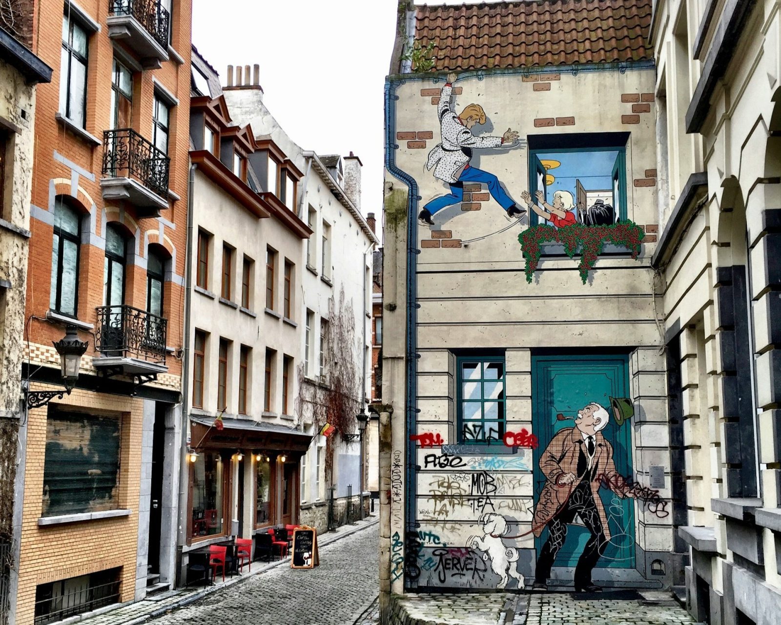 Foto de rua de paralelepípedo com um grafite em um dos muros.