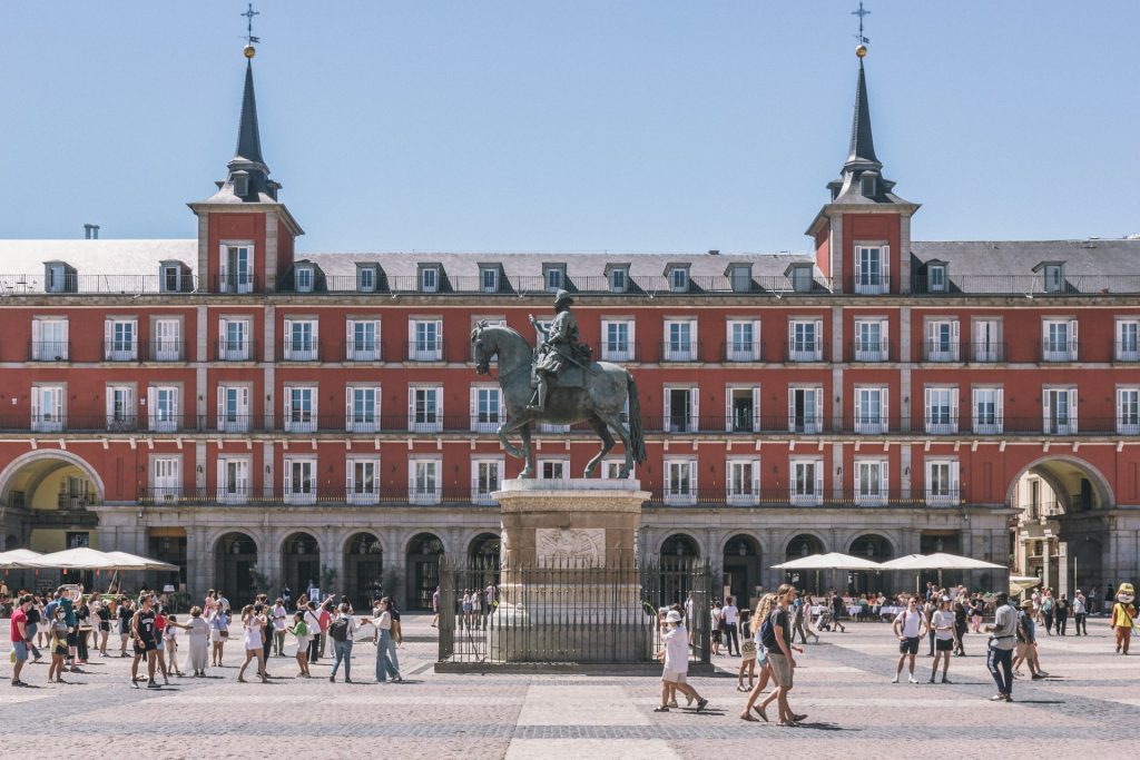 Plaza mayor Madrid. Foto de uma praça com uma estatua em frente a um edificio terracota