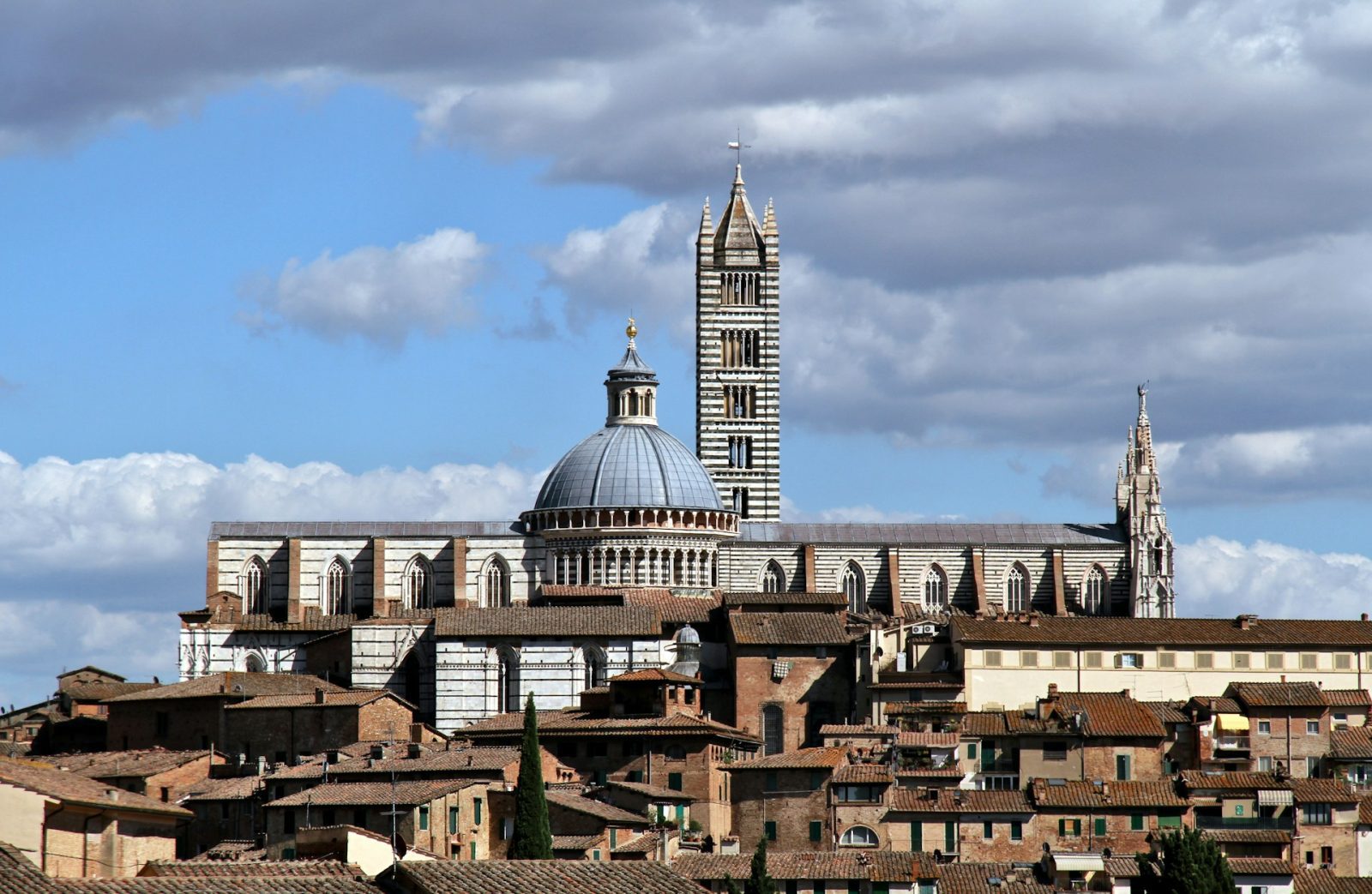 Siena. foto de construção com listras pretas e brancas e uma torre alta.