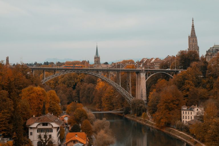 Berna. Foto de uma paisagem com uma grande ponte e vegetação alaranjada.