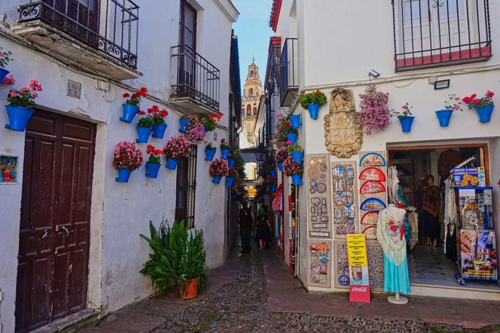 Córdoba. Foto de rua estreita de paralelepipedo com uma loja de artesanato na esquina.