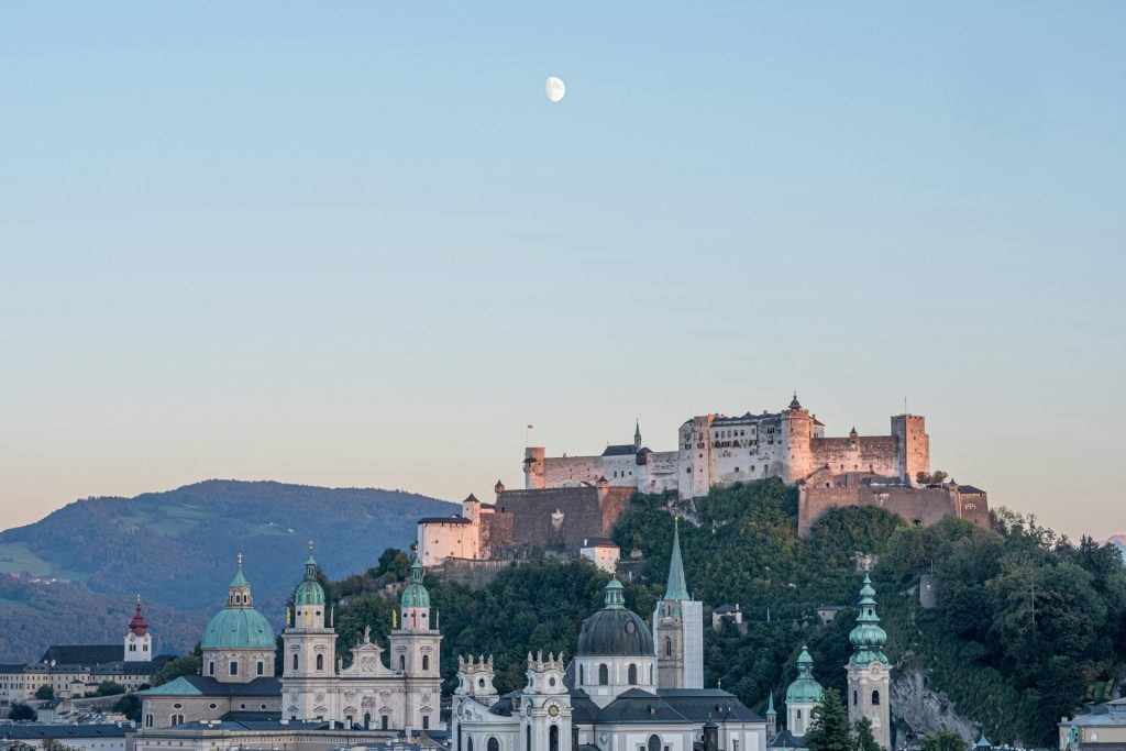 Fortaleza Salzburgo. Foto de paisagem com telhados verdes e construção murado non topo da colina.