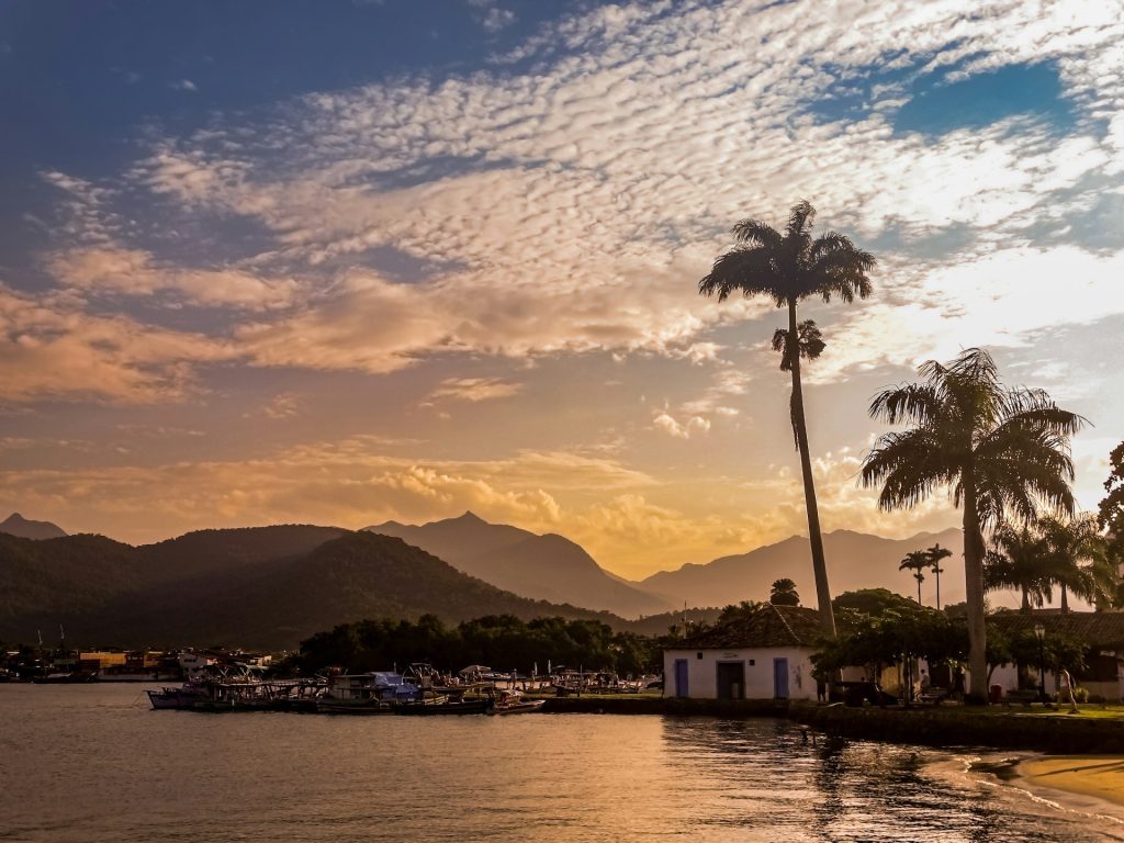 Paraty. foto de praia com uma casa branco ao fundo no entardecer.