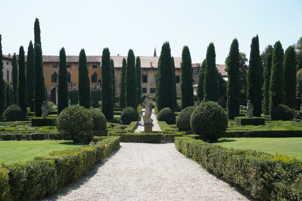 Verona. Jardim com escultura de uma mulher no meio.