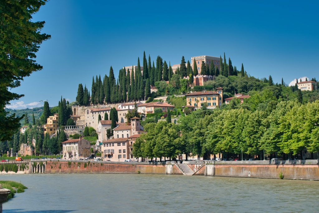 Verona. paisagem de casas e arvores na margem de um rio.