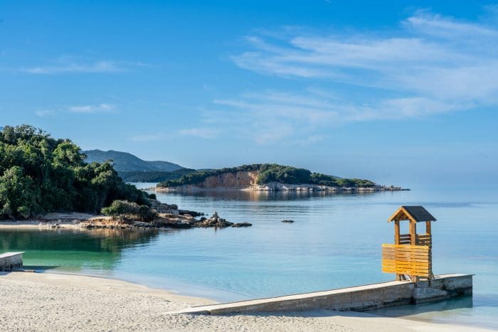 Albania. Foto de corpo de agua com pequeno branco de madeira na areia.