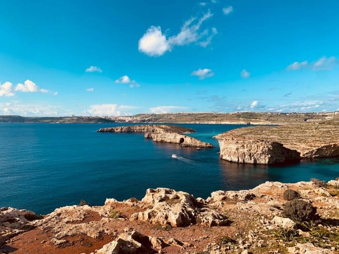 Comino. Corpo de agua com algumas formações rochosas no meio da agua.