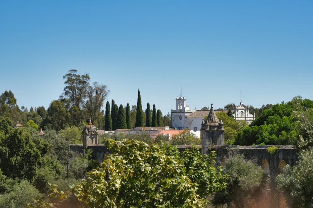 Evora. foto de uma ponte com contrução branca ao fundo e vegetação verde na frente.