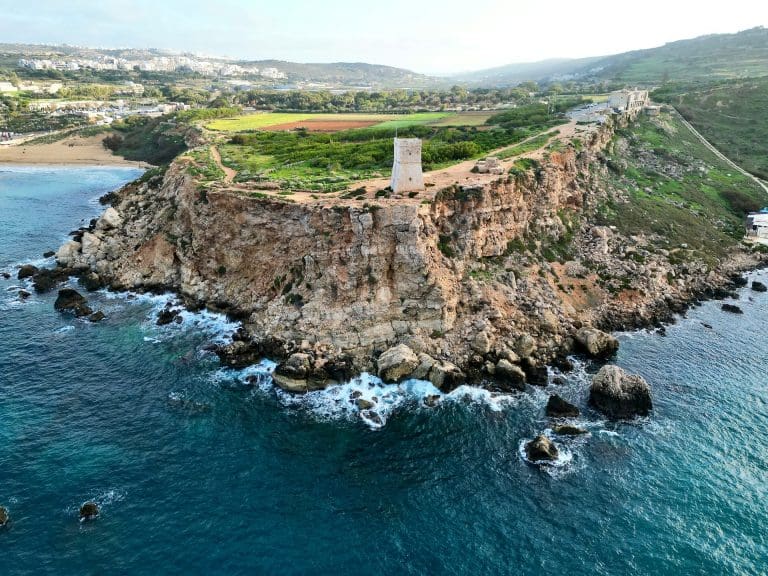 Golden Bay. Formação rochosa com pequena torre de pedra na beira de um corpo de agua